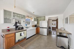 a large kitchen with white appliances and wooden cabinets at Jensen House - Incredible Desert Views home in Joshua Tree +18 photos