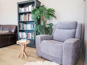 a living room with a chair and a book shelf with books at Holiday Home Orphée by Interhome in Telgruc-sur-Mer