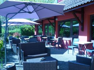 ein Restaurant mit Tischen, Stühlen und einem Sonnenschirm in der Unterkunft The Originals City, Hôtel Mulhouse Est in Rixheim