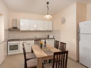 Una cocina con una mesa con sillas y un refrigerador. en Holiday Home Danijel by Interhome, en Sukošan