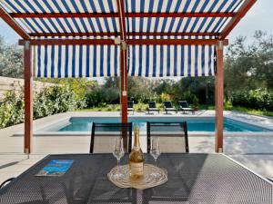 Una botella de vino en una mesa junto a una piscina. en Holiday Home Danijel by Interhome, en Sukošan