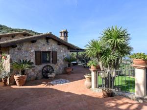 a stone house with palm trees and a fence at Villa Ricali by Interhome in Porto Santo Stefano