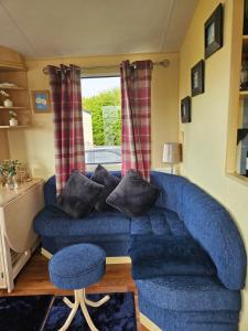 a blue couch in a living room with a window at Daisy Lodge Lilac Grove 3 in Waxholme