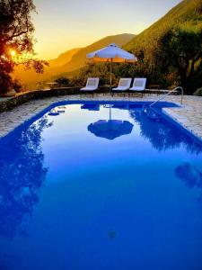 a blue pool with two chairs and an umbrella at Spartilas Villas in Pyrgi