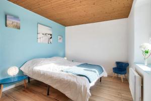 Maison pour 6 avec jardin, terrasse et jeux في Saint-Frégant: غرفة نوم بسرير وجدار ازرق