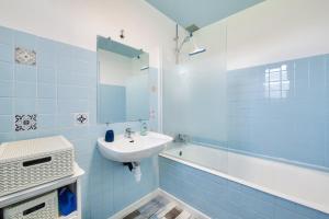 Maison pour 6 avec jardin, terrasse et jeux في Saint-Frégant: حمام من البلاط الأزرق مع حوض استحمام وحوض استحمام