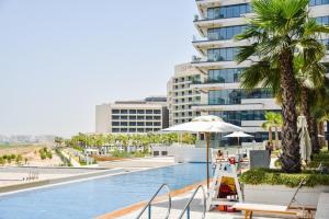 ein Pool mit einem Gebäude im Hintergrund in der Unterkunft Voyage Studio In Mayan With Partial Ocean Views in Abu Dhabi