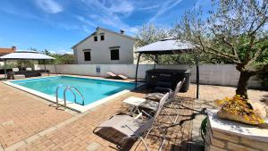 a swimming pool with two chairs and an umbrella at Apartments Kimm's Hideaway in Poreč