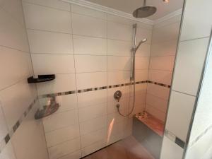 a shower in a white tiled bathroom at Ferienwohnung AusZeit 1 in Ainring +15 photos