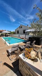 a swimming pool with two chairs and a table at Apartments Kimm II in Poreč