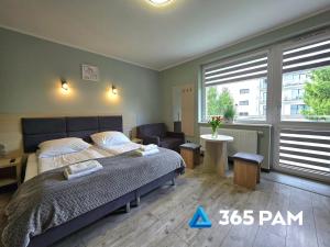 a bedroom with a bed and a table and two windows at 365PAM - Studio C35 Dominikana in Sianozety