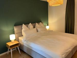 a bedroom with a large white bed with two lamps at Olea Prien - Chiemsee Apartment in Prien am Chiemsee