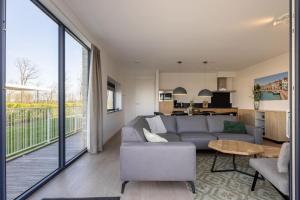 sala de estar con sofá gris y cocina en Hello Zeeland - Veerse Wende - Lamsoor 15, en Arnemuiden 24 fotos más