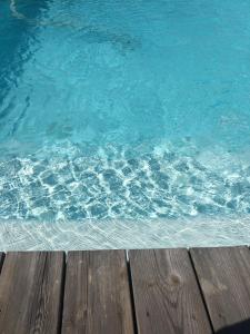 a pool of blue water next to a wooden deck at Hotel l'Isolella in Porticcio