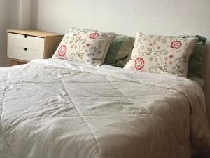 a white bed with two pillows and a night stand at Departamento Moreno in Rosario +11 photos