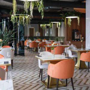 ein Restaurant mit Tischen, Stühlen und Pflanzen in der Unterkunft Apartament Latte z Sauną i Siłownią - Jezioro Żywieckie, Laguna Beskidów in Zarzecze