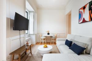 a living room with a white couch and a tv at Alcântara Urban Retreat in Lisbon