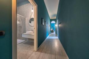 un bagno con pareti blu e un corridoio con lavandino di ApartmentsArena - Corte delle Arti a Verona