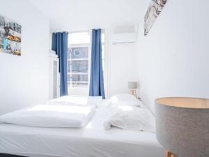 una camera da letto con un letto con lenzuola bianche e una finestra di Apartment Malecot I by Interhome a Blankenberge