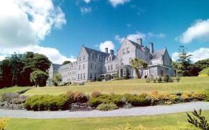 una grande casa in cima a una collina erbosa di Park Hotel Kenmare a Kenmare