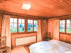 um quarto com paredes de madeira, uma cama e janelas em Chalet La Capsule by Interhome em Les Collons