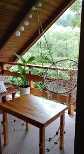 a porch with a swing and a table and a plant at Kaczmarówka in Mchawa