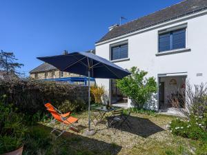 Un patio con una mesa y sillas y una sombrilla. en Holiday Home Le Verger by Interhome, en Carnac
