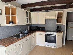 a kitchen with white cabinets and a sink at Comfortable countryside gite access to jacuzzi in Asnois +16 photos