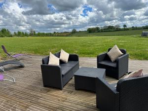 three chairs and a table on a patio with a field at Comfortable countryside gite access to jacuzzi in Asnois
