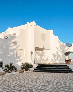 a white building with stairs in front of it at Villa Les Étoiles, Djerba in El Guecheïne