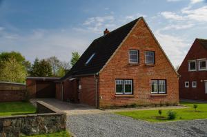 a red brick house with a black roof at Ferienhaus Nordische Ruhe in Kaiser Wilhelm Koog