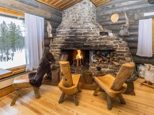 a living room with a stone fireplace in a log cabin at Holiday Home Villa kopararova by Interhome in Saariselka