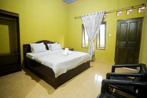 a bedroom with a bed and a window and a chair at Senaru Gateway homestay in Senaru