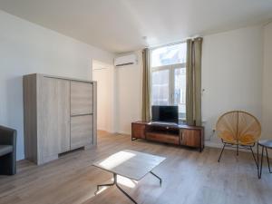 a living room with a tv and a table and a chair at Apartment Malecot II by Interhome in Blankenberge +25 photos