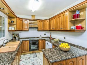 a kitchen with wooden cabinets and a bowl of fruit on the counter at Holiday Home Bon repos by Interhome in Cunit