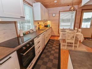 a kitchen with white cabinets and a dining table at Holiday Home Huvila tornionjoen rannalla by Interhome in Pello