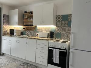 a kitchen with white cabinets and a stove and a refrigerator at Relaxxa Apartman in Noszvaj
