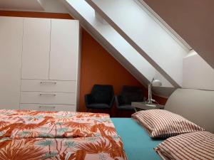 a attic bedroom with a bed and two chairs at Ferienwohnung Munzert - Bodensee in Langenargen