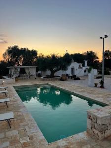 a swimming pool in a yard with a sunset in the background at Trullo Tatauan in San Michele Salentino