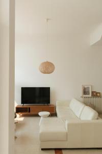a white living room with a white couch and a tv at Casa Isa Bela in Buarcos