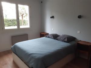 a bedroom with a bed with two pillows and a window at Maison 8 personnes in Mézos +4 photos
