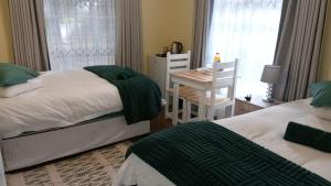 a bedroom with two beds and a table and a chair at The Haven Guesthouse 2 in Estcourt +32 photos