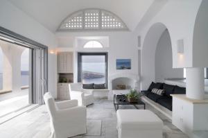a living room with white furniture and a large window at Beautiful Oia Villa in Oia