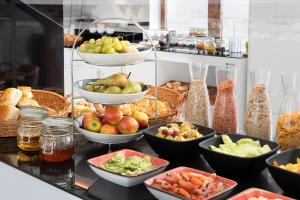 a buffet with bowls of fruits and vegetables on a counter at INNSiDE by Meliá Leipzig in Leipzig
