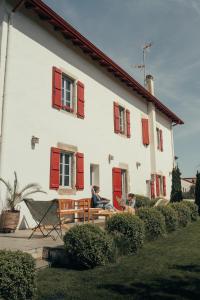 two people sitting on a bench in front of a house at Maison d'hôtes PACHAMAMA in Ahetze