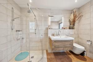 ein Badezimmer mit Dusche, Waschbecken und Toilette in der Unterkunft PINTO ROSSO - rotes Strandhaus an idyllischem Privatsee in Twist + 14 Fotos