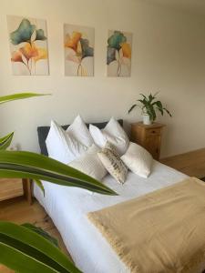 a bedroom with a white bed with four paintings on the wall at Gästehaus am See in Radolfzell am Bodensee