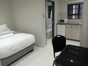 a bedroom with a bed and a table and a microwave at Hayat Hotel 94Juta in Johannesburg