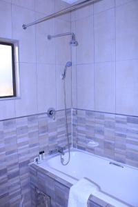 a bathroom with a bath tub with a shower at JTown CBD Self-Catering Apartment in Jwaneng