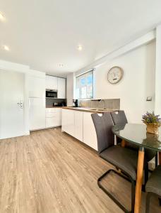 cocina con armarios blancos, mesa y reloj en Be Happy, Santa Pola Apartamento a 50 metros de la Gran Playa, en Santa Pola